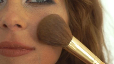 Makeup artist using cosmetic brush for makeup face to young woman. Close up Stock Footage 91653696
