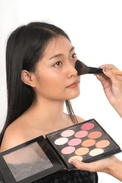Makeup artist is using cosmetics makeup blush on face beautiful young Asian w Stock Photos