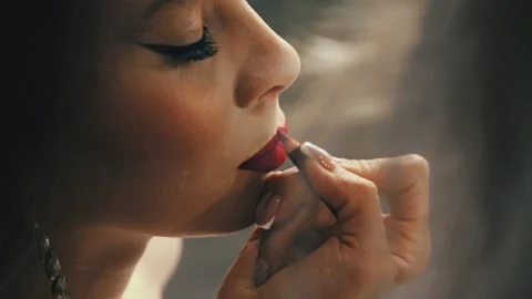A makeup artist works with precision, transforming a young woman with bright Stock Footage 321373783