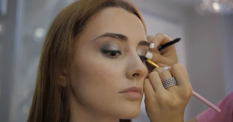 Makeup artists applies eyeshadows on young woman eyes Stock Footage 124260926