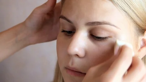 Makeup artist's hand does concealer around the eye model close plan Stock Footage 101650271