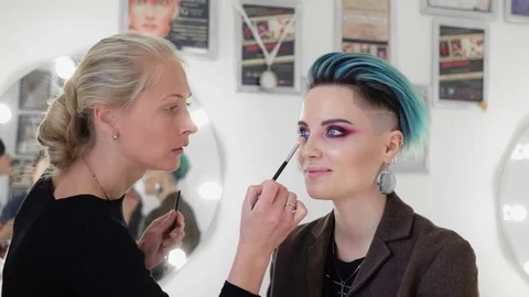 Makeup artists at work making smoky eyes on beautiful model with blue hair Stock Footage 80759822