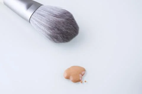 A makeup brush and a drop of Foundation for the face on an isolated background Stock-Fotos