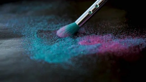 Makeup brush and shiny pink and blue sparkles on a black background. Stock Footage 237780617