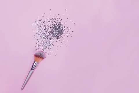 Makeup brush and strar shapped small confetti on pastel pink background. Stock Photos