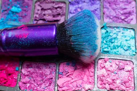 Makeup brush close-up on the background of broken eye shadows. Cosmetic brush Foto stock