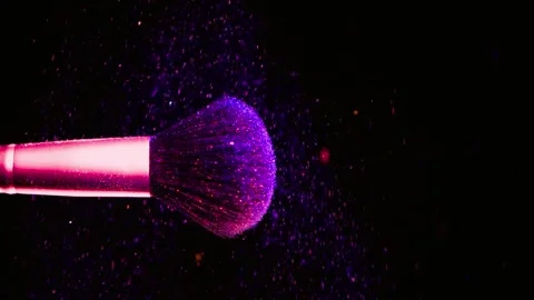 Makeup brush hitting purple glitter powder on black background video Stock Footage 341802118