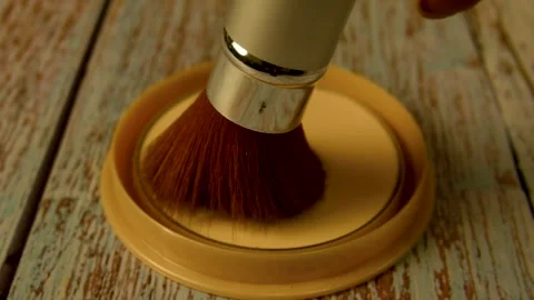 The makeup brush moves over the box of powder. Applying Powder to the Face Video stock 254005563