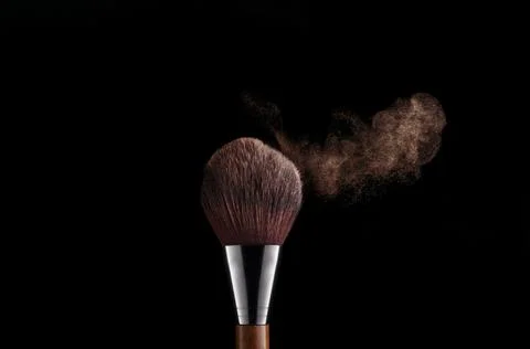 Makeup brush with powder explosion on black background Stock Photos
