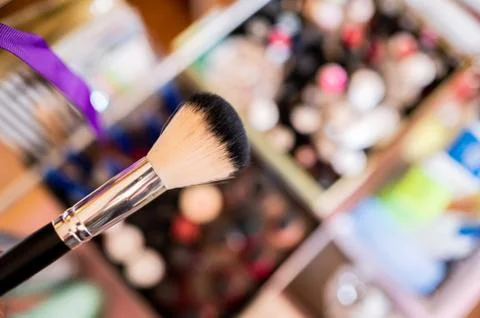 Makeup brush with unfocused background with many personal beauty products. Stock Photos