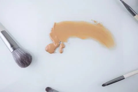 Makeup brushes and a smear of Foundation on a white background Stock-Fotos