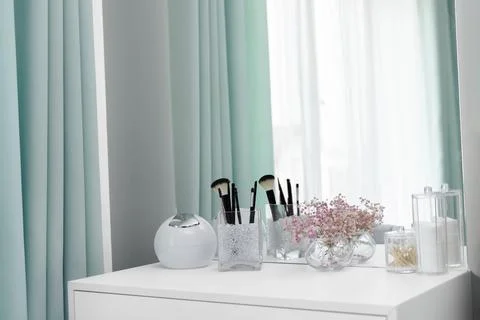 Makeup brushes are in a standing vase on a dressing table Stock Photos