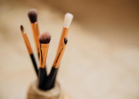 Makeup brushes close-up. Blurred beige background made of kraft paper. Stock Photos