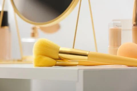 Makeup brushes on dressing table in room, closeup Stock Photos