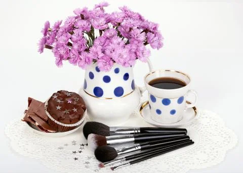 Makeup brushes, flowers and cup of coffee with cupcake Foto stock