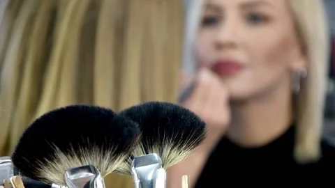 Makeup brushes in the foreground, in the background, a makeup artist paints Stock Footage 143505750