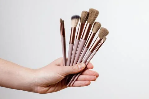 Makeup brushes in hand on a gray plain background Foto stock