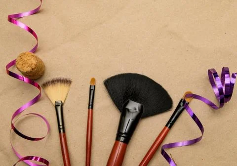 Makeup brushes lie on craft paper with holiday ribbon and champagne cork Stock Photos