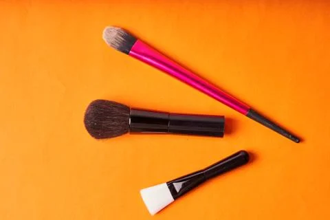Makeup brushes on orange background. Tools for cosmetic procedures Stock Photos