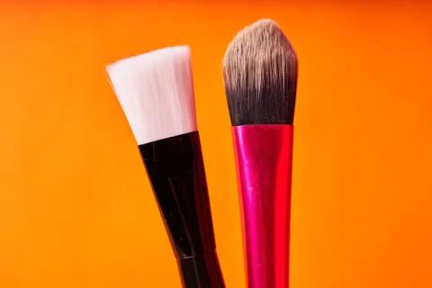 Makeup brushes on orange background. Tools for cosmetic procedures Stock Photos