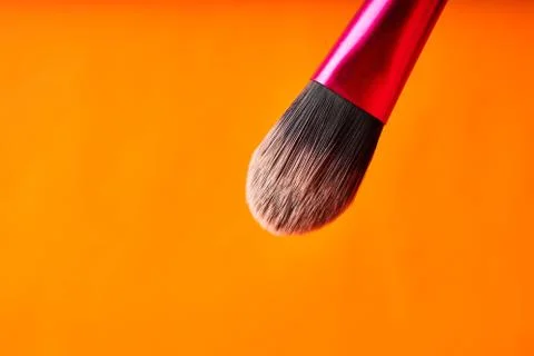 Makeup brushes on orange background. Tools for cosmetic procedures Stock Photos