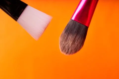 Makeup brushes on orange background. Tools for cosmetic procedures Stock Photos