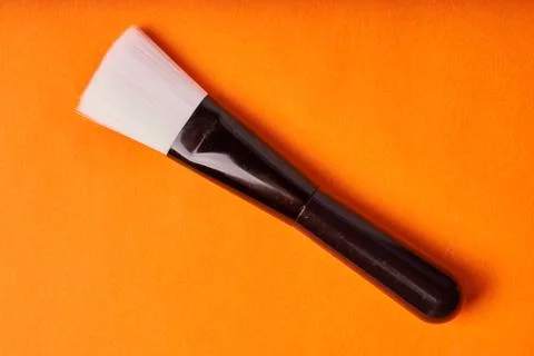 Makeup brushes on orange background. Tools for cosmetic procedures Stock Photos