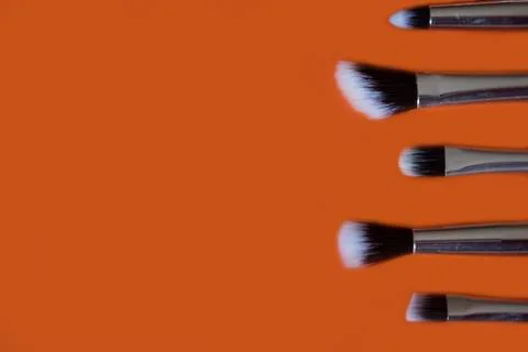 Makeup brushes on orange background.Copy space Stock Photos