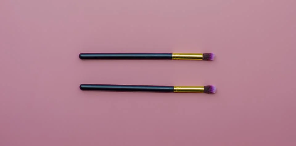 Makeup brushes on pink colored composed background. Top view Stock Photos