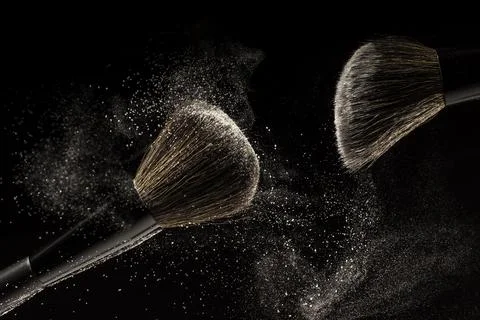 Makeup brushes, powder particles dynamically in the air. Spray cosmetics. Fro Stock Photos