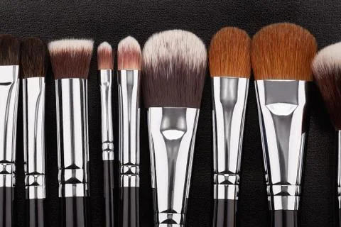 Makeup brushes set on black leather background Stock Photos
