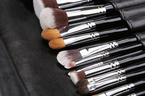 Makeup brushes set on black leather background Stock Photos