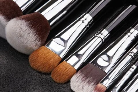 Makeup brushes set on black leather background Stock Photos