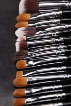 Makeup brushes set on black leather background Stock Photos