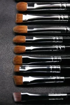 Makeup brushes set on black leather background Stock Photos