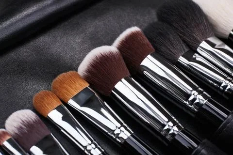 Makeup brushes set on black leather background Stock Photos
