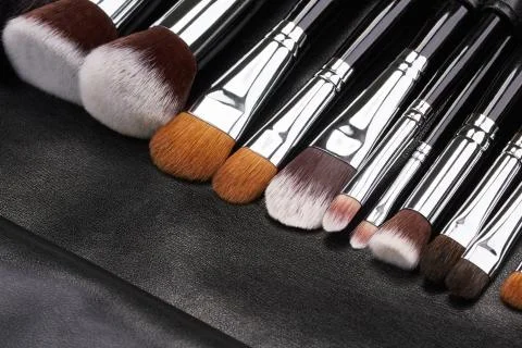 Makeup brushes set on black leather background Stock Photos