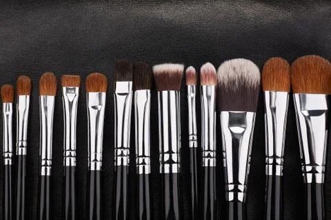 Makeup brushes set on black leather background Stock Photos