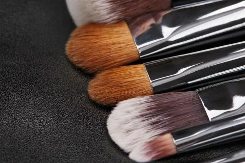 Makeup brushes set on black leather background Stock Photos