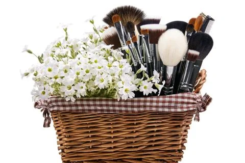 Makeup brushes set in crib with flowers. Chickweed. Isolated. White background Stock Photos