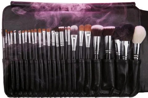 Makeup brushes set in leather case. Pink smoke. Isolated. White background Stock Photos
