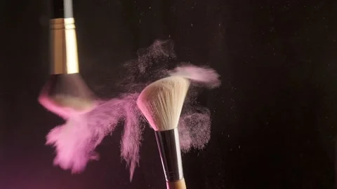 Makeup brushes touch each other on dark background and small particles of Stock Footage 194395325