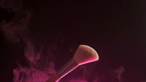Makeup brushes touch each other on dark background and small particles of Stock Footage 194395840