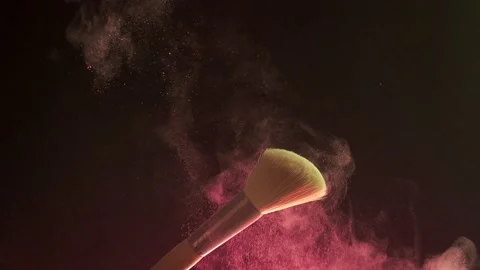 Makeup brushes touch each other on dark background and small particles of Stock Footage 194396014