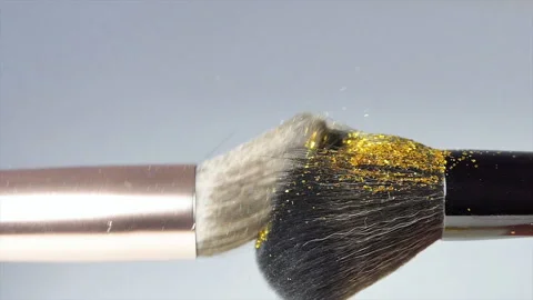 Makeup brushes touch each other on a white background and small particles of Stock Footage 228433952