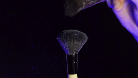 Makeup brushes touch each other on dark background and small particles of Stock Footage 229296280