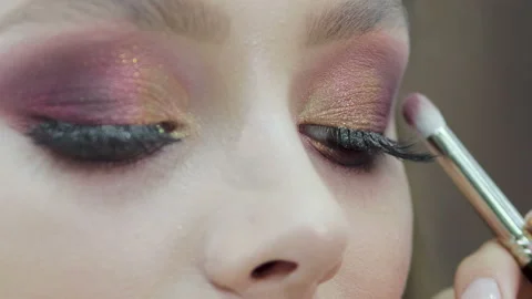 Makeup closeup. Cosmetic eye shadow and eye brush. Transformation of a girl with Vídeos de archivo 115338759