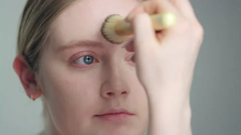 Makeup demonstration: ￼Pretty blonde model applies foundation with large brush Stock-Footage 193932026