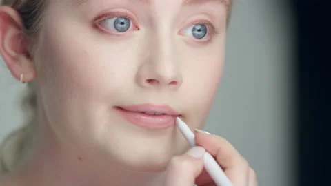 Makeup demonstration: ￼Pretty blonde model applies lip liner in studio Stock Footage 193947955