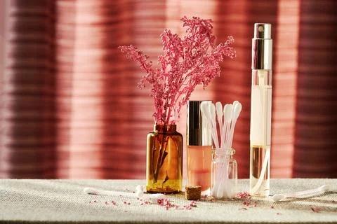 Makeup desk with tiny perfume jar, lip gloss, cotton buds and lilac branch Stock Photos